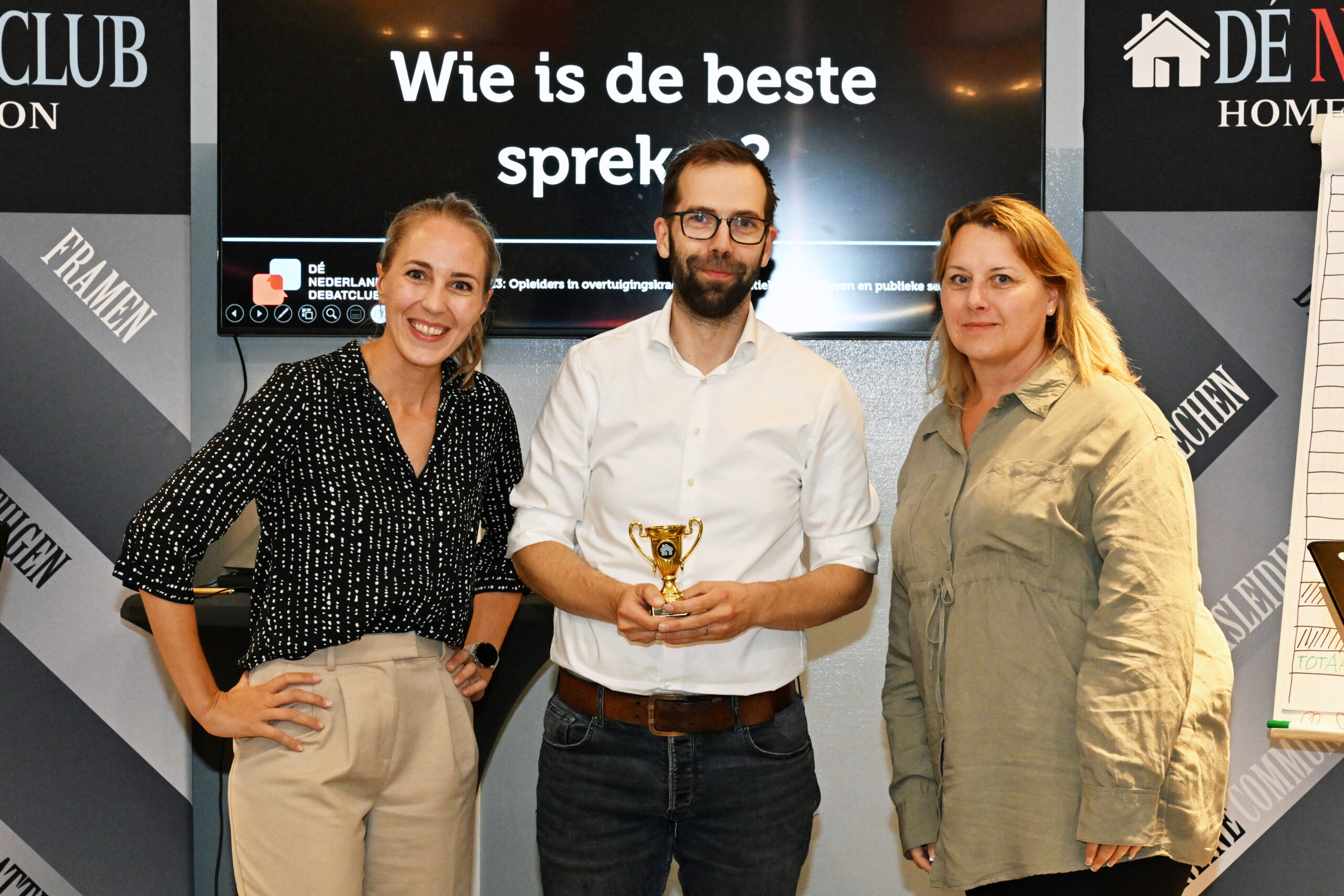 Joris Stok ontving de prijs voor de Beste Spreker van de avond. Leonie Veerman (l) en Roos Zitman (r) overhandigden hem de dik verdiende beker. Dit gebeurde tijdens The Sizzling And Surprising Season Finish van Dé Nederlandse Debatclub in Amsterdam.